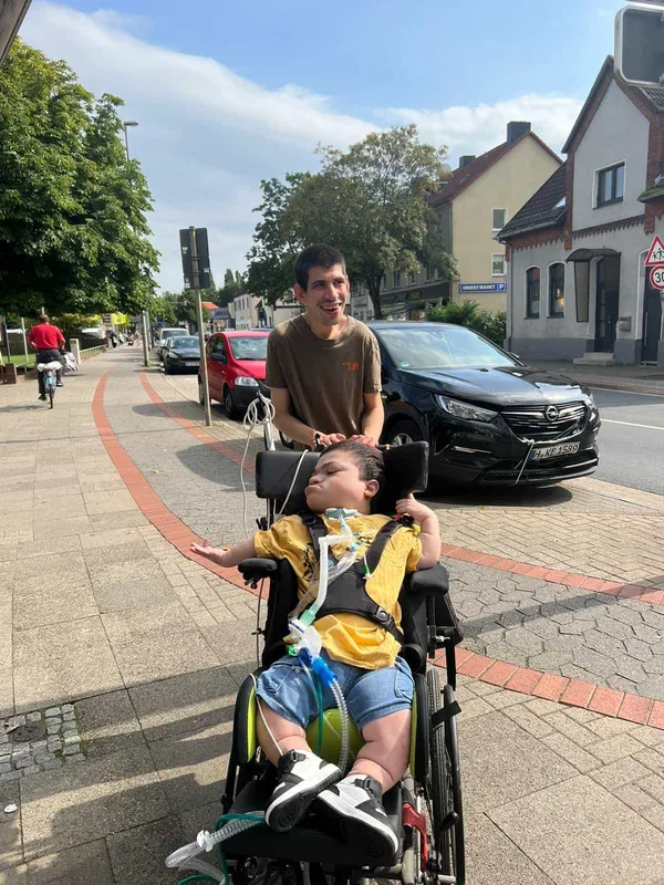 Ein Kind von zwei unserer Patienten, einer im Rollstuhl einer hinter ihm